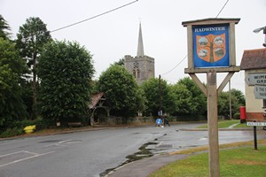 02-07-2025, Village sign met daar achter de St. Mary the Virgin kerk